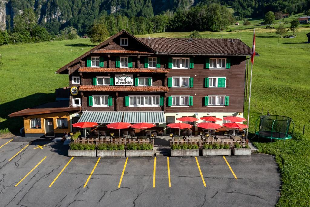 a hotel with red umbrellas in a parking lot at Hotel Alpenblick Muotathal in Muotathal
