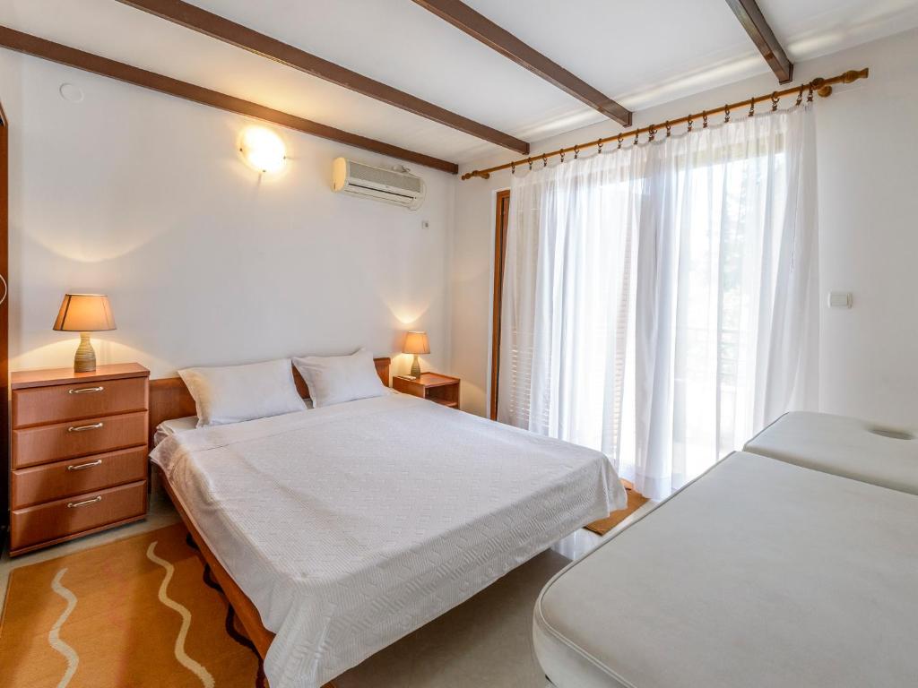 1 dormitorio con 2 camas y ventana en Captain Apartments, en Budva