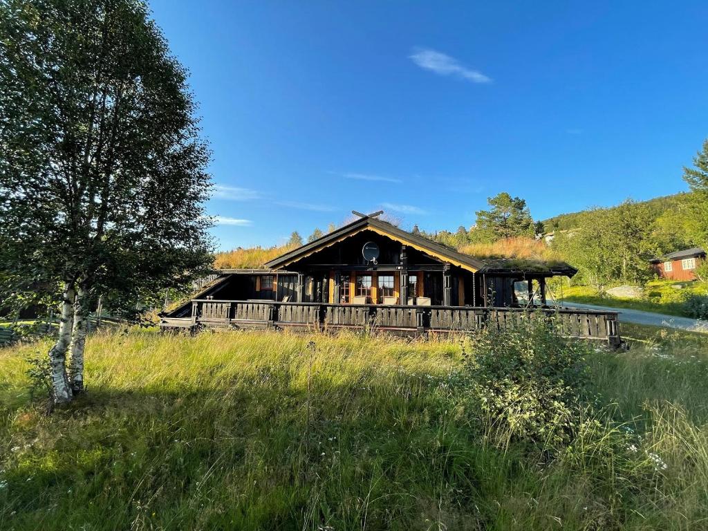 a large wooden house in a field with a tree at Sundebu, Spacious 5-Bedroom mountain cabin near Ski and Hiking in Rauland