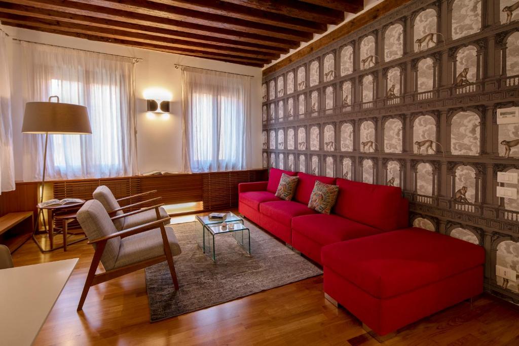 ein Wohnzimmer mit einem roten Sofa und einem Stuhl in der Unterkunft Ca' della Scimmia - Rialto Bridge, Venice in Venedig
