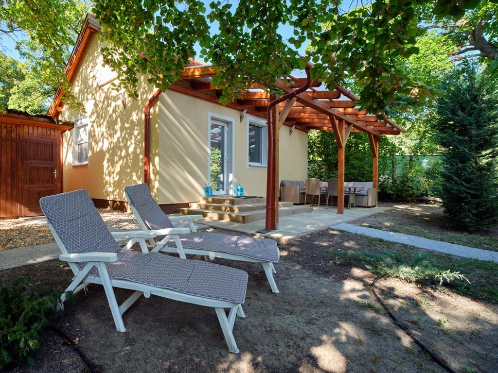 un patio con 2 sillas, una mesa y una pérgola en Fövenyes House, en Balatonudvari