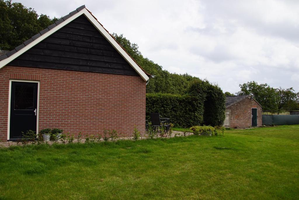 ein rotes Backsteinhaus mit einem Rasenplatz in der Unterkunft Zur Grünen Heide in Wellerlooi