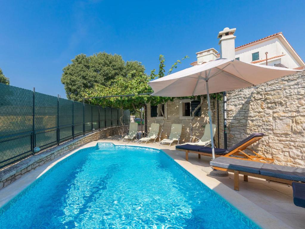 a swimming pool with an umbrella next to a house at Holiday Home Villa Lancin - RCA453 by Interhome in Divšići