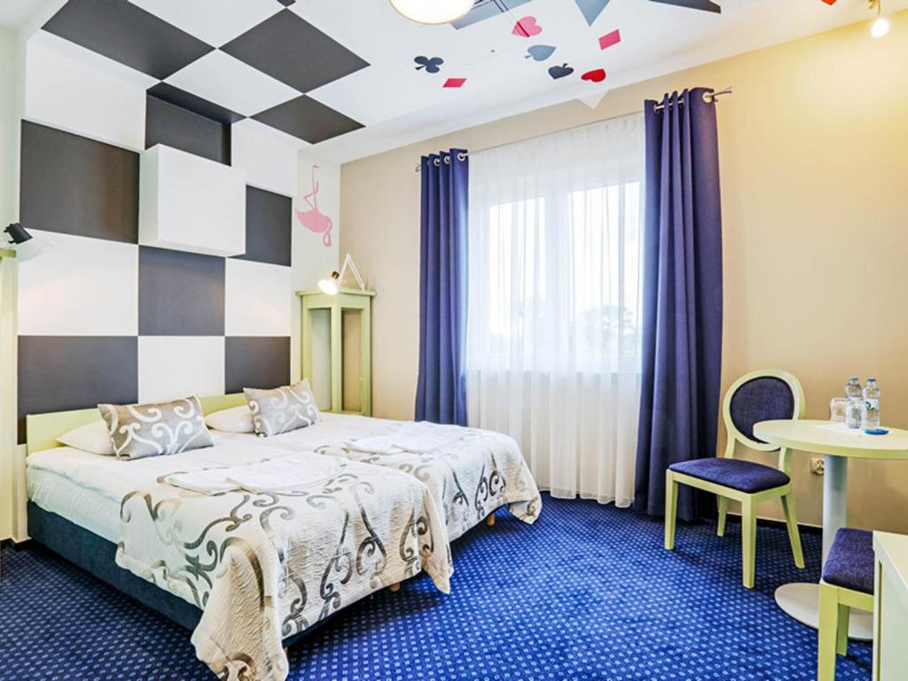 a bedroom with a bed and a checkerboard wall at Hotel Magiczny Zakątek in Raszowa