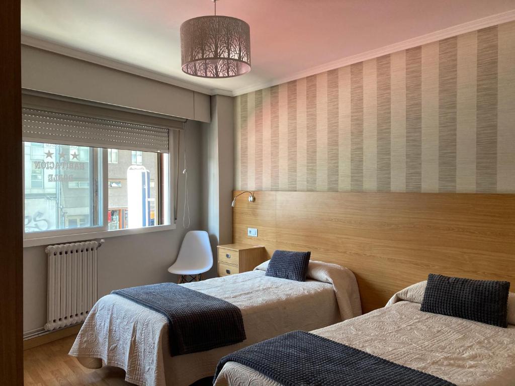 une chambre d'hôtel avec deux lits et une fenêtre dans l'établissement Hostal Crisol X Liste Station, à La Corogne