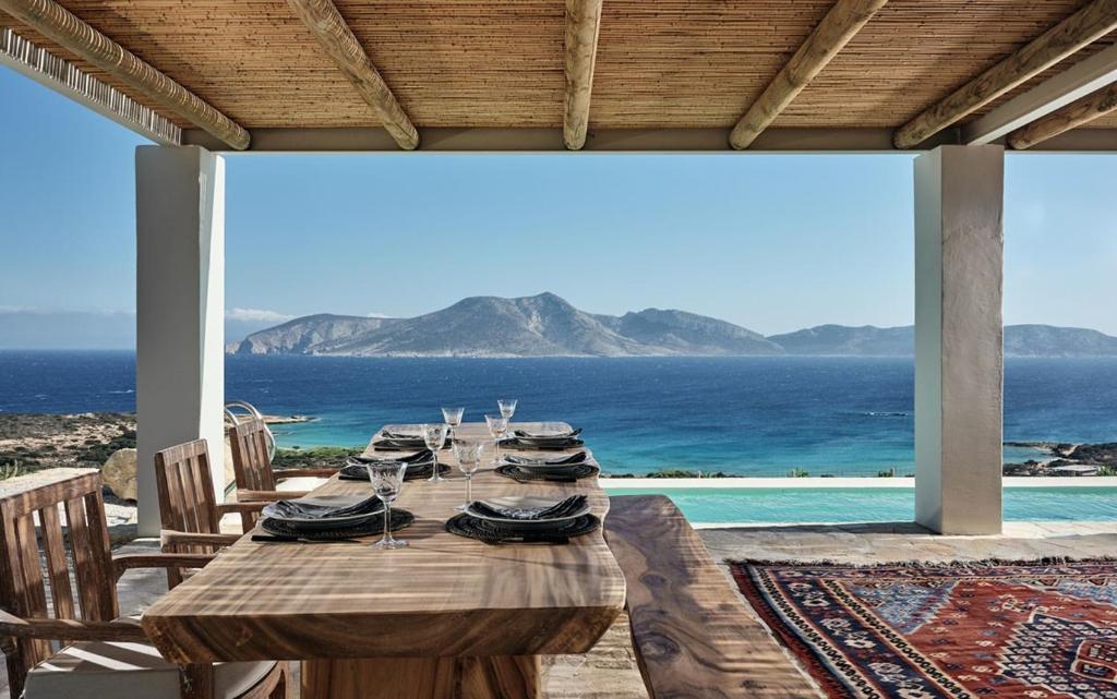 a wooden table with chairs and a view of the ocean at Koufonisi Villas in Koufonisia