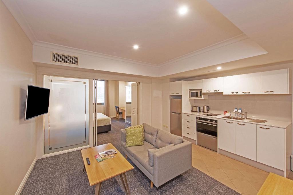 uma cozinha e sala de estar com um sofá e uma mesa em Quality Apartments Adelaide Central em Adelaide