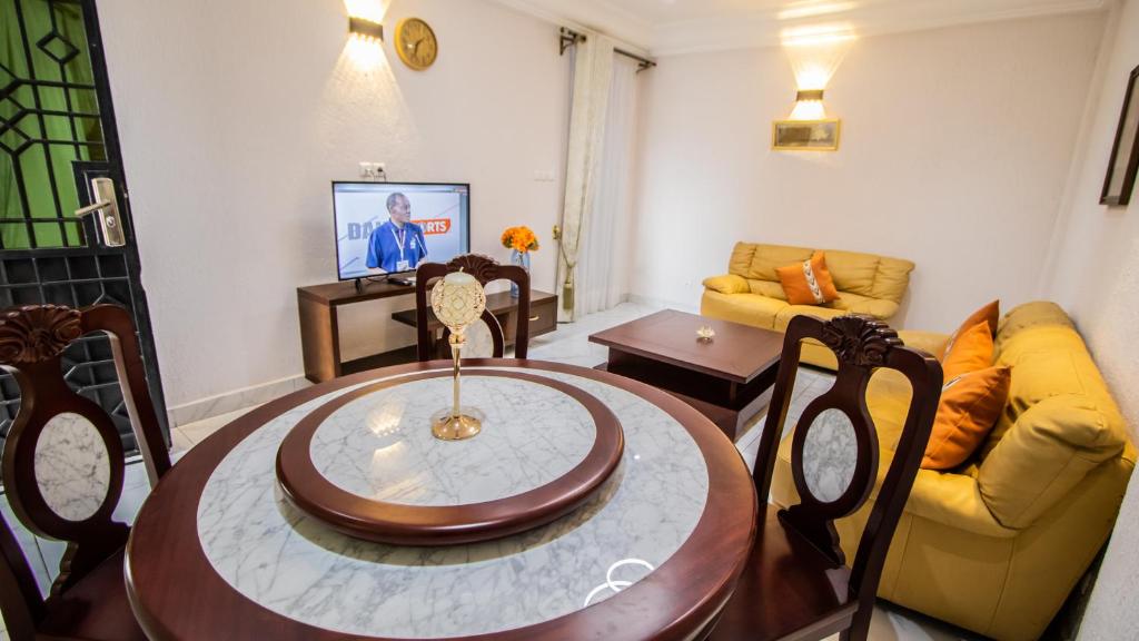 uma sala de estar com uma mesa e um sofá amarelo em Residence Le Bonheur - Serviced apartment by Douala Airport/Mall em Douala