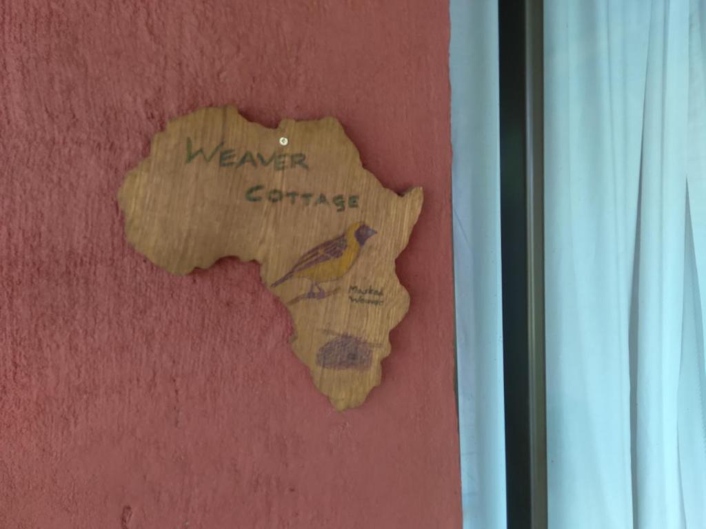 a sign on a red wall with a bird on it at Non Stop Adventures Weaver Cottage in Pietermaritzburg