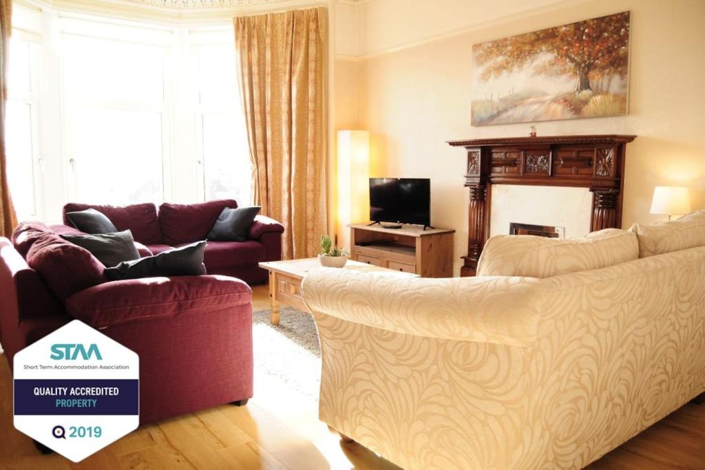 a living room with two couches and a tv at A Spacious Flat with Character - Private Car Space in Paisley