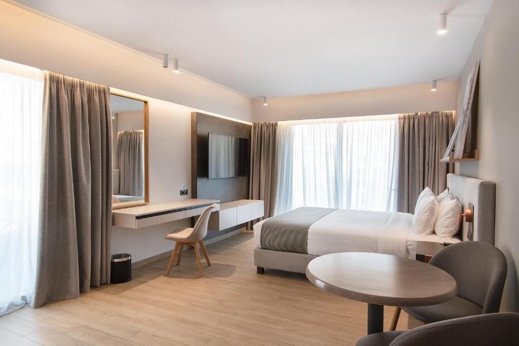 um quarto de hotel com uma cama, uma secretária e uma mesa em The Residences Kalamata em Kalamata