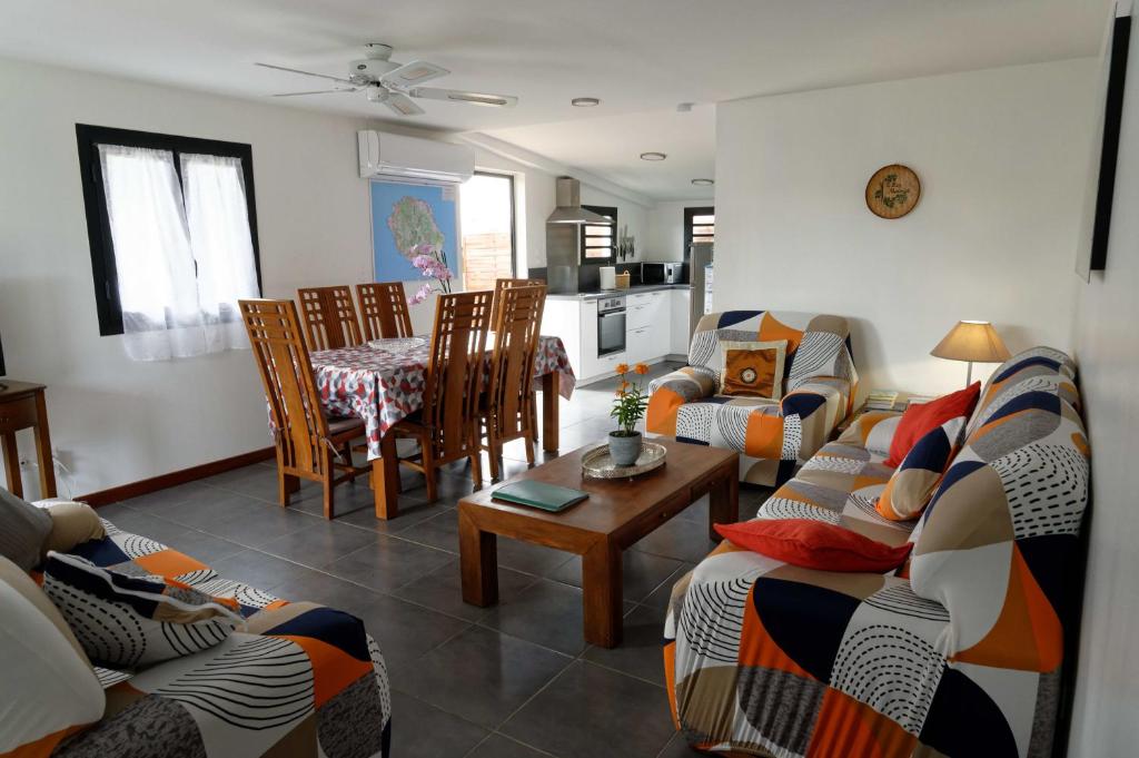 a living room with a couch and a table and chairs at Gîte TI KAZ MORINGA, Entre Volcan, Cilaos et Sud sauvage in Saint-Louis