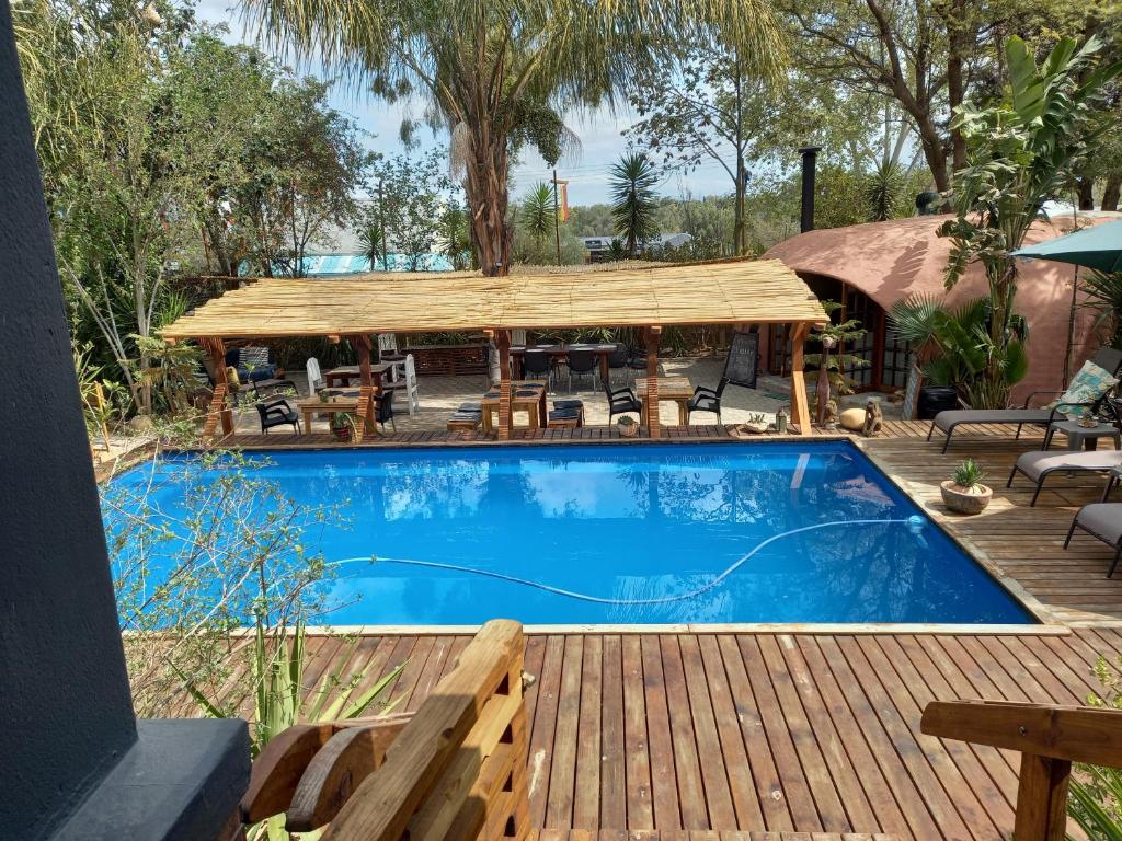 a swimming pool with a wooden deck and a picnic table at Karoozin Village in Oudtshoorn