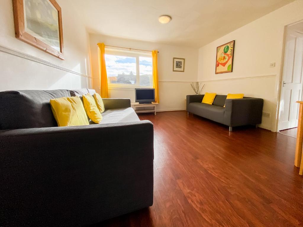 - un salon avec un canapé noir et des oreillers jaunes dans l'établissement Glasgow Green Park Home, à Glasgow
