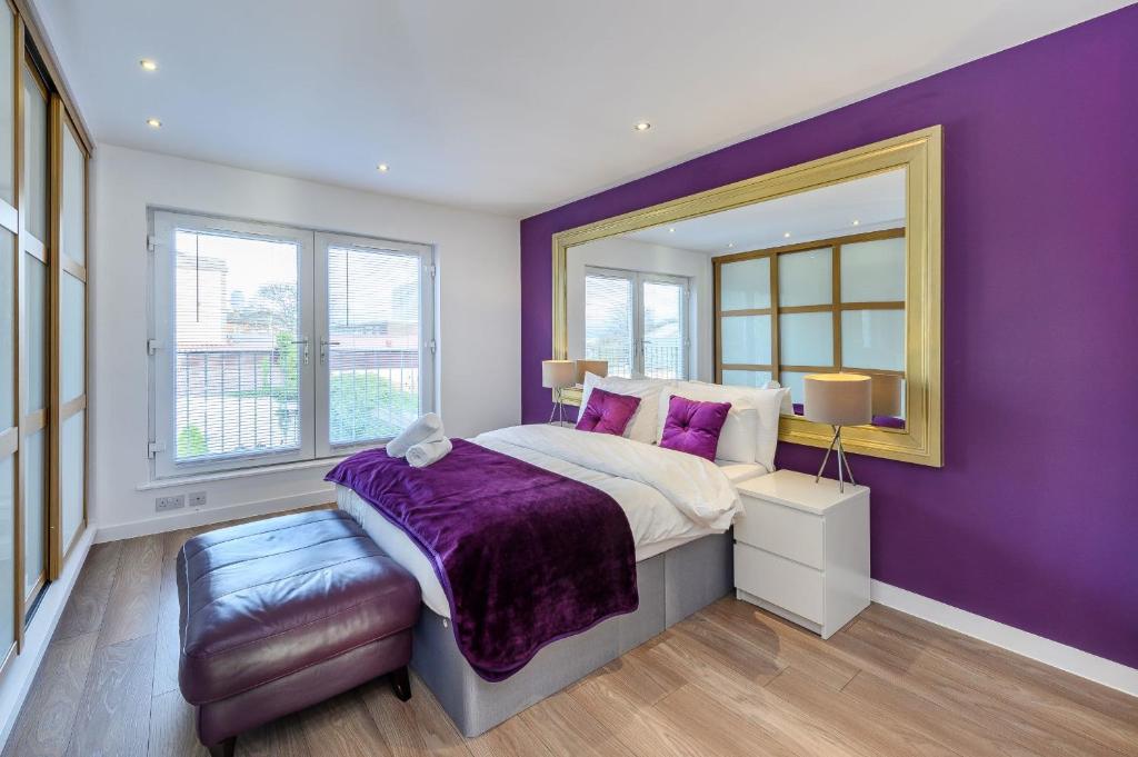 a purple bedroom with a bed and a mirror at Mosspark Boulevard Exec Apartment ii - Free Parking in Glasgow