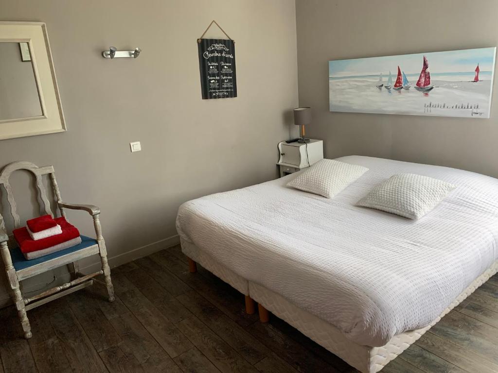a bedroom with a white bed and a chair at Le cadran in Stella-Plage
