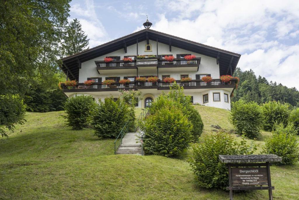 ein Haus auf einem Hügel mit einem Schild davor in der Unterkunft Ferienwohnung Stigloher im Bergschlößl in Oberaudorf