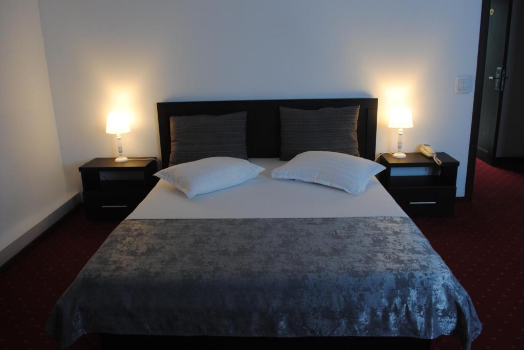 ドロベタ・トゥルヌ・セヴェリンにあるHotel Coronaのベッドルーム1室(大型ベッド1台、ナイトスタンド2台付)