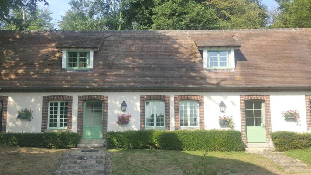 une maison blanche avec des portes et des fenêtres vertes dans l'établissement CHAMBRE D'HOTE AU MOULIN DE LONGUEIL, à Longueil