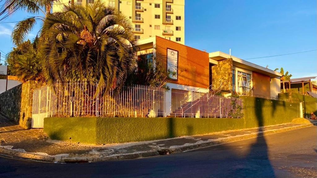 a palm tree in front of a building with a fence at Nova Pousada Consulado in Ponta Grossa