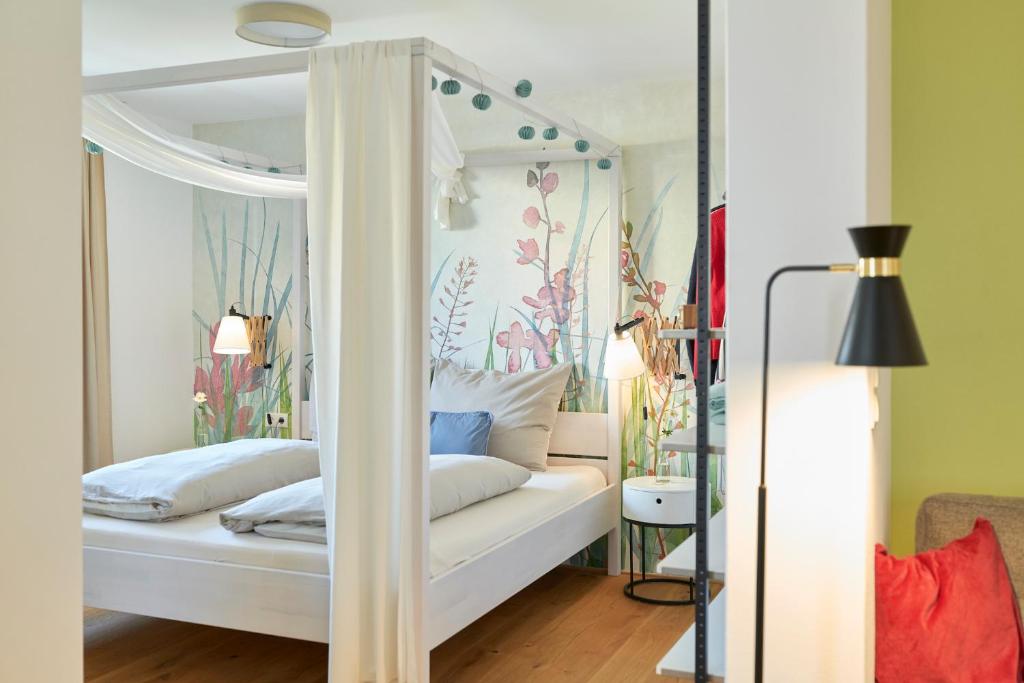 una camera da letto con un letto a baldacchino bianco e fiori di Rotes Haus Bregenz Garten Wohnung a Bregenz