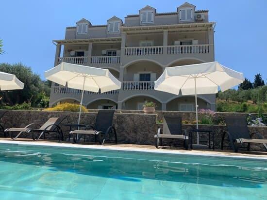 un hotel con una piscina con sillas y sombrillas en Hibiscus Suites en Gouvia