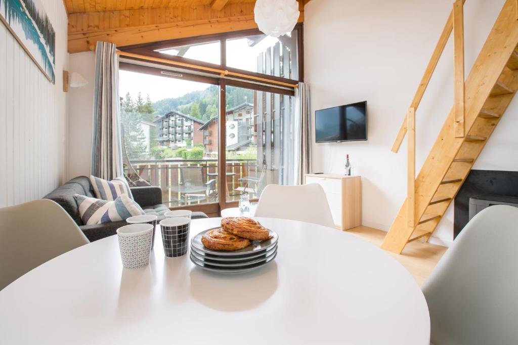 a white table with a plate of food on it in a living room at Stunning renovated studio with mezzanine in Morzine
