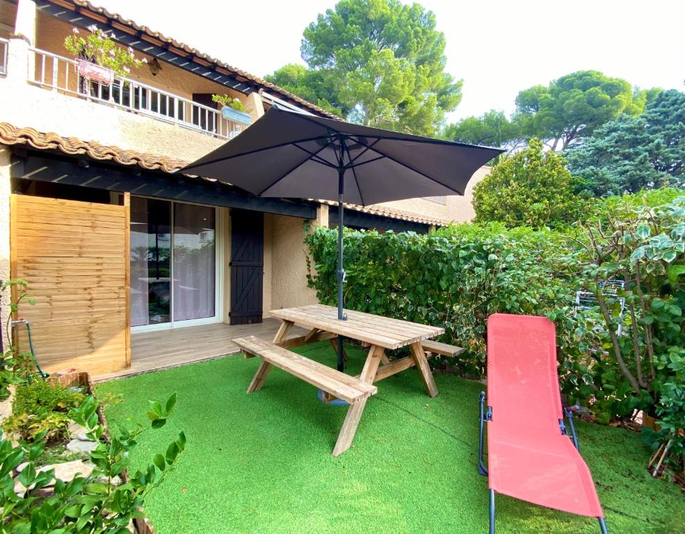 einem Picknicktisch aus Holz mit einem Regenschirm und einer roten Rutsche in der Unterkunft SUPERBE LOGEMENT CLIMATISE à 2 PAS DE LA MER in Saint-Cyr-sur-Mer