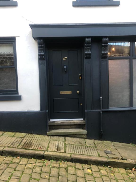 una puerta negra en un edificio blanco con una acera de ladrillo en Former 16th Century Inn - In the heart of Macclesfield, gateway to the Peaks en Macclesfield