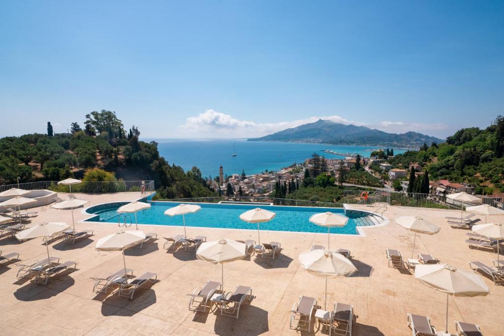 einen großen Pool mit Stühlen und Sonnenschirmen in der Unterkunft Avalon Palace Hotel - Adults Only in Zakynthos