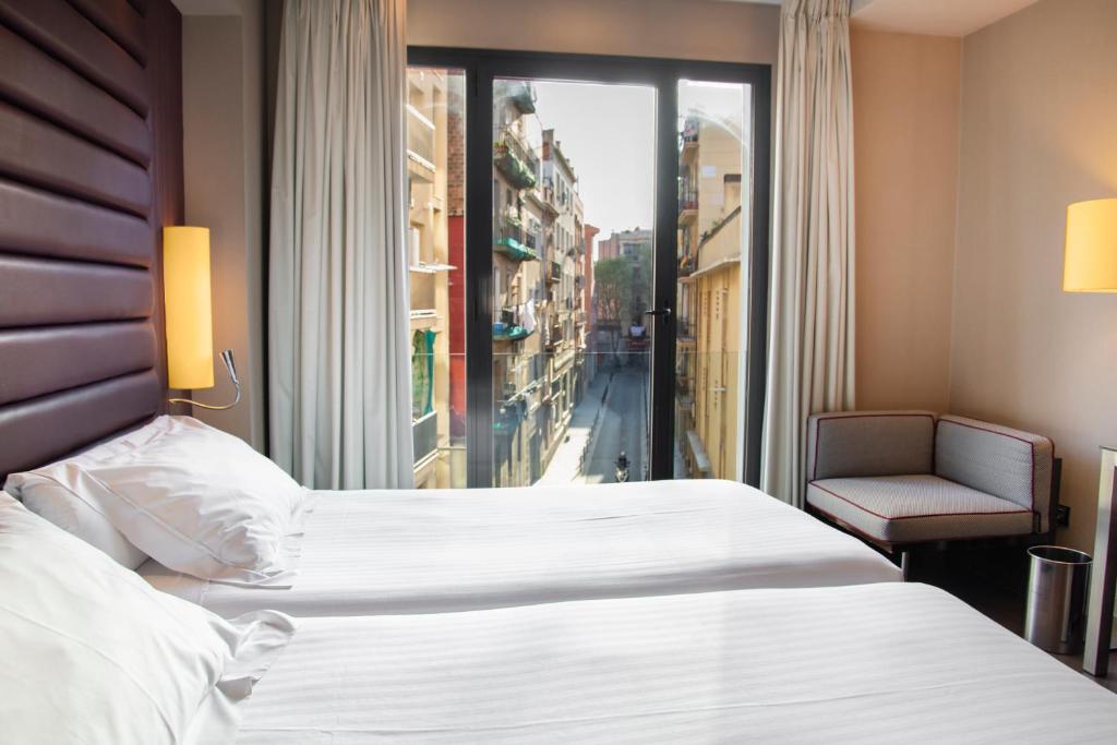 a hotel room with a large bed and a window at Pestana Arena Barcelona in Barcelona