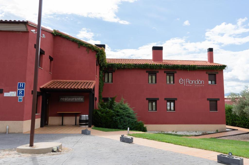 un edificio rojo con un banco delante de él en Hotel El Rondón, en Cebreros