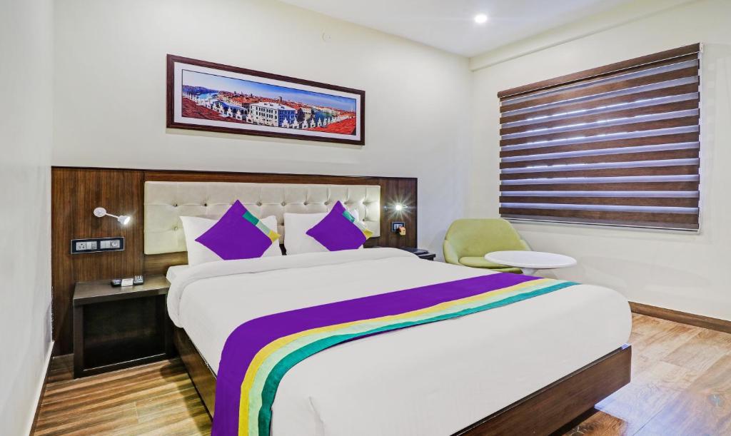 una camera da letto con un grande letto con cuscini viola di Treebo Tryst Raj Vista Global Village a Bangalore