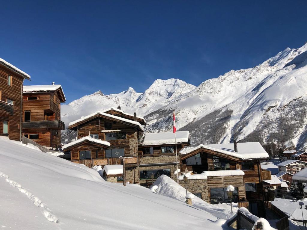 a ski lodge with snow covered mountains in the background at Boutique Lodge Spycher in Saas-Fee