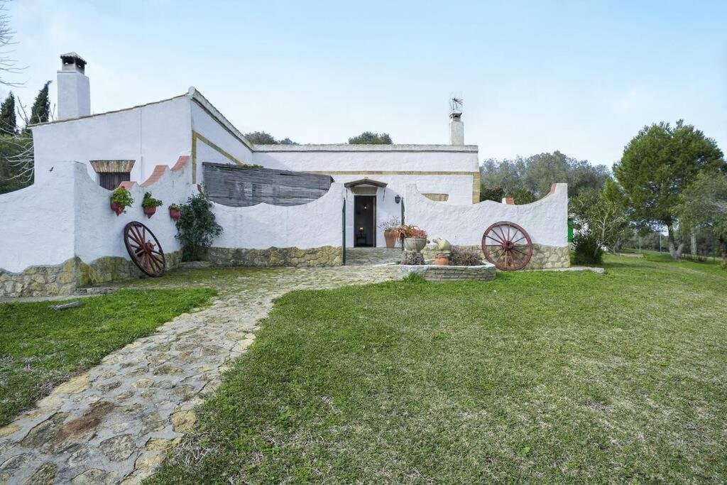 Uma casa branca com um jardim de relva à frente. em casa rural el niño Santamaría , con piscina y wifi em Vejer de la Frontera