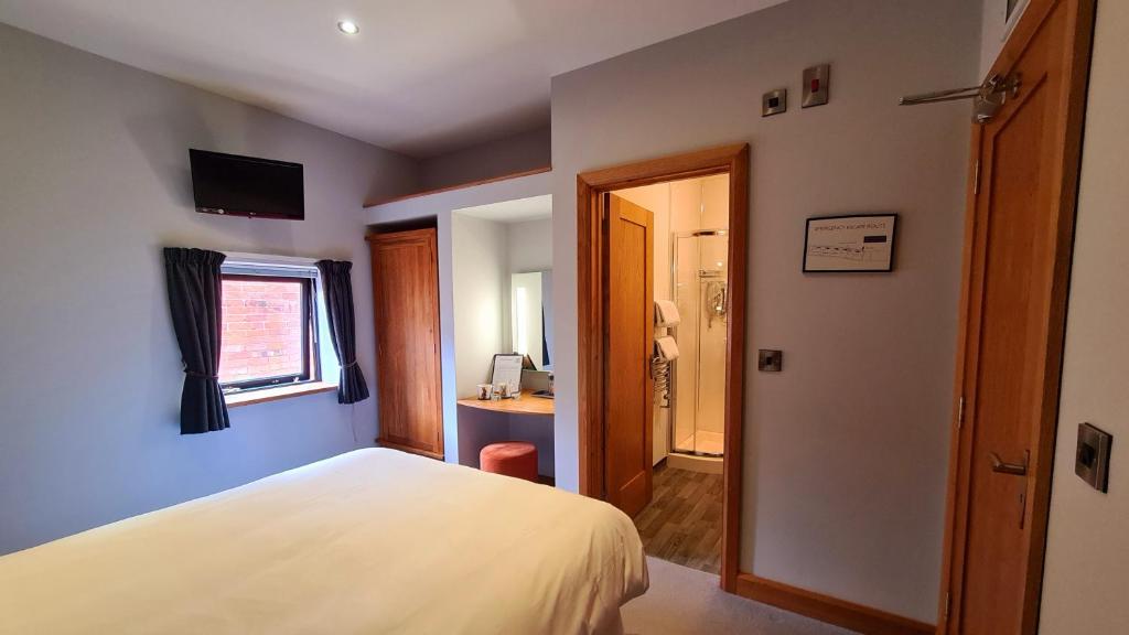a bedroom with a white bed and a bathroom at Rutland Rooms in Oakham