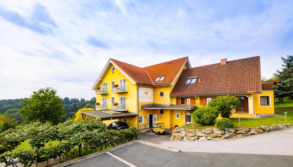 una casa amarilla con techo marrón en Golf & Thermenland Sonnenpension Frühstückshotel Burgauberg Stegersbach en Stegersbach