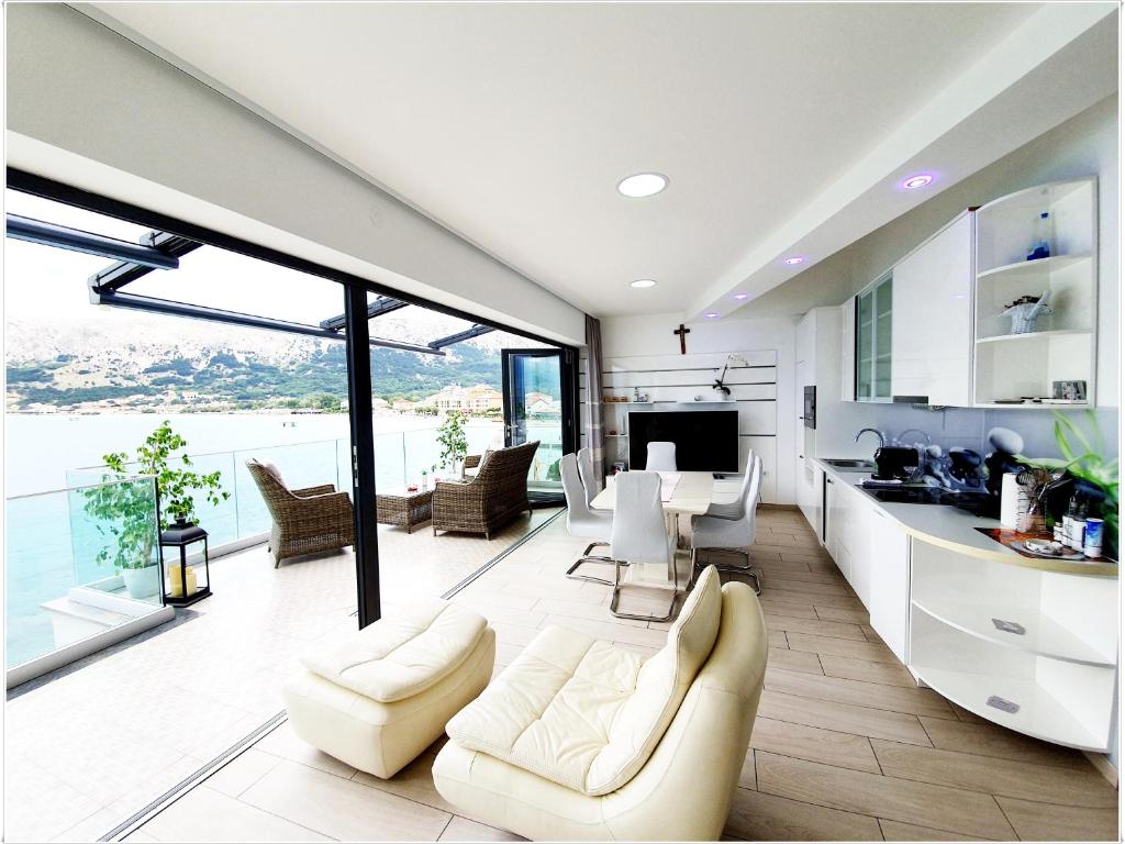 a living room with white furniture and a large window at Apartments Palada 1 in Baška