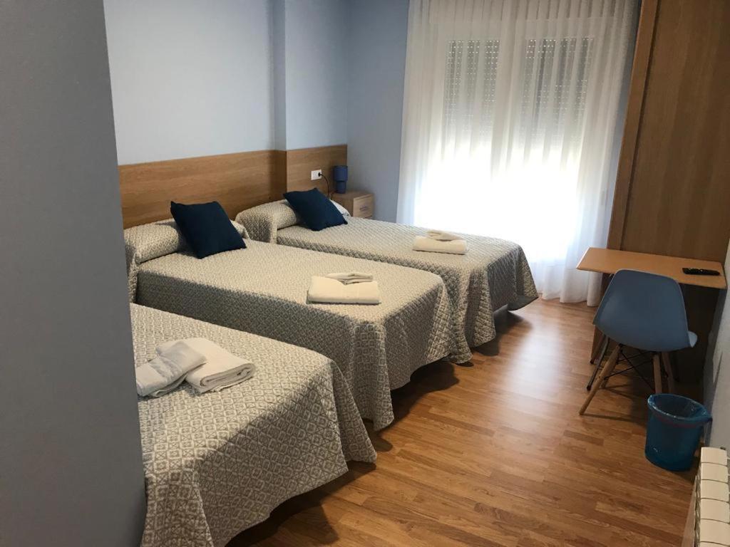 a room with three beds with napkins on them at Pensión Santirso in Palas de Rei