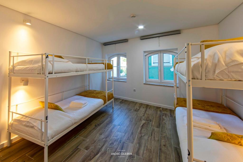 a room with three bunk beds and a wooden floor at Host'olaria in Lamego