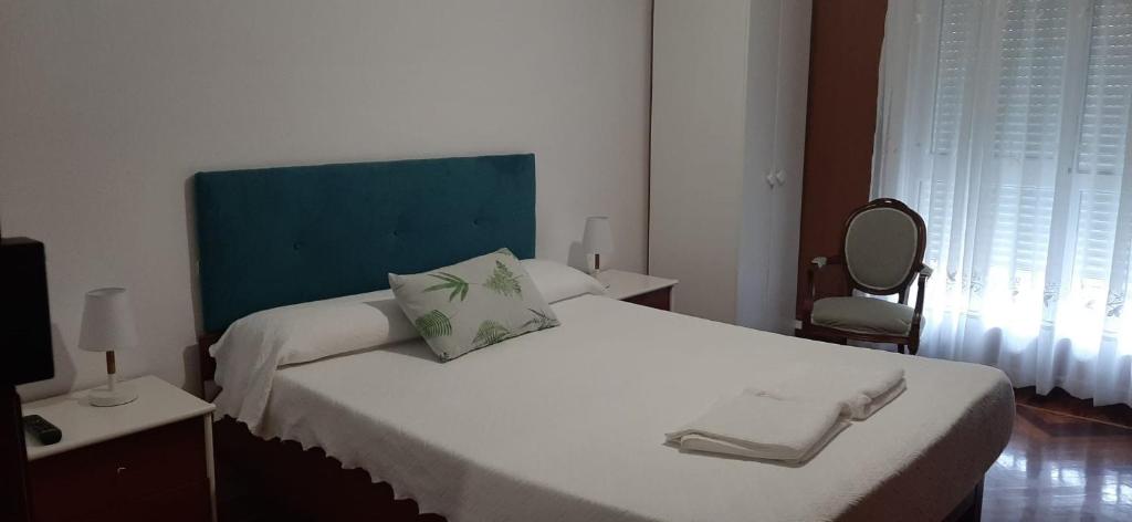 a bedroom with a large white bed with a blue headboard at ALOJAMIENTO CASA LEÓN in Santoña