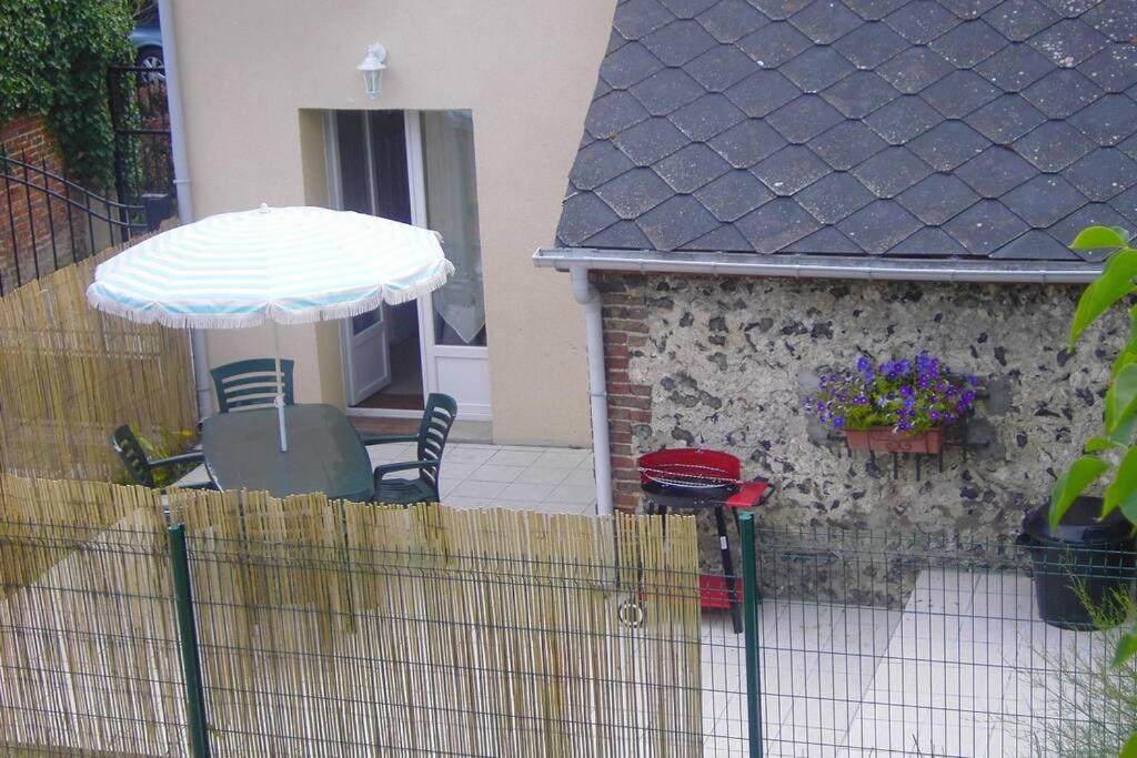 濱海克里耶勒的住宿－Maison Le four à chaux，一个带遮阳伞和椅子的庭院和一座房子