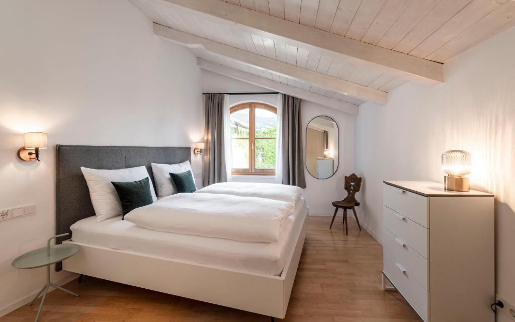 a white bedroom with a large bed and a window at Brixen City Maisonette in Bressanone