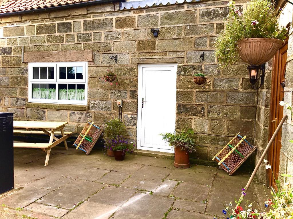 um pátio com uma porta branca, uma mesa e cadeiras em Wheelhouse - Grinkle Bell Cottage em Saltburn-by-the-Sea