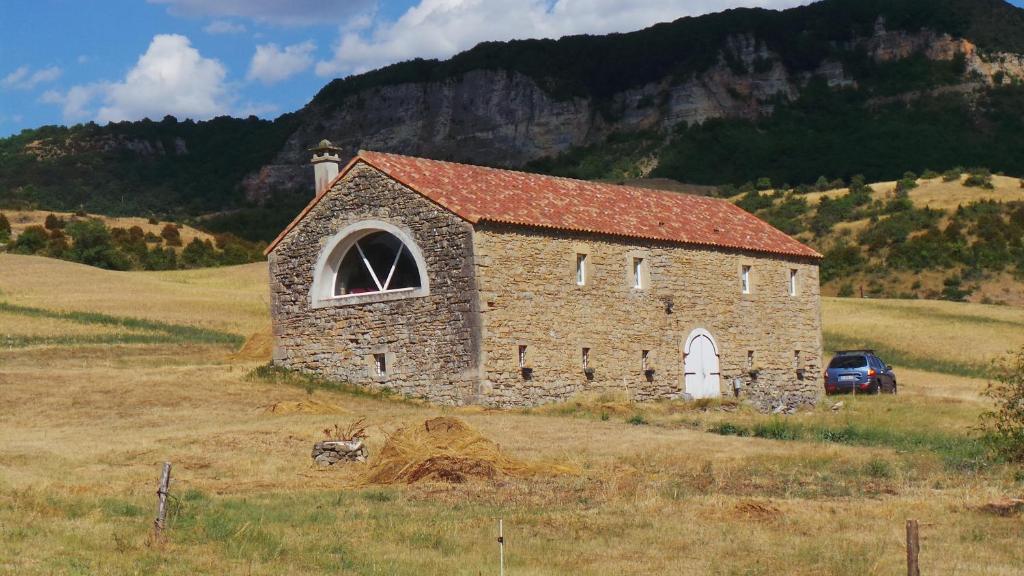 una vecchia chiesa di pietra in mezzo a un campo di Chambre d'hôtes LES LOUVES a Saint-Paul-des-Fonts