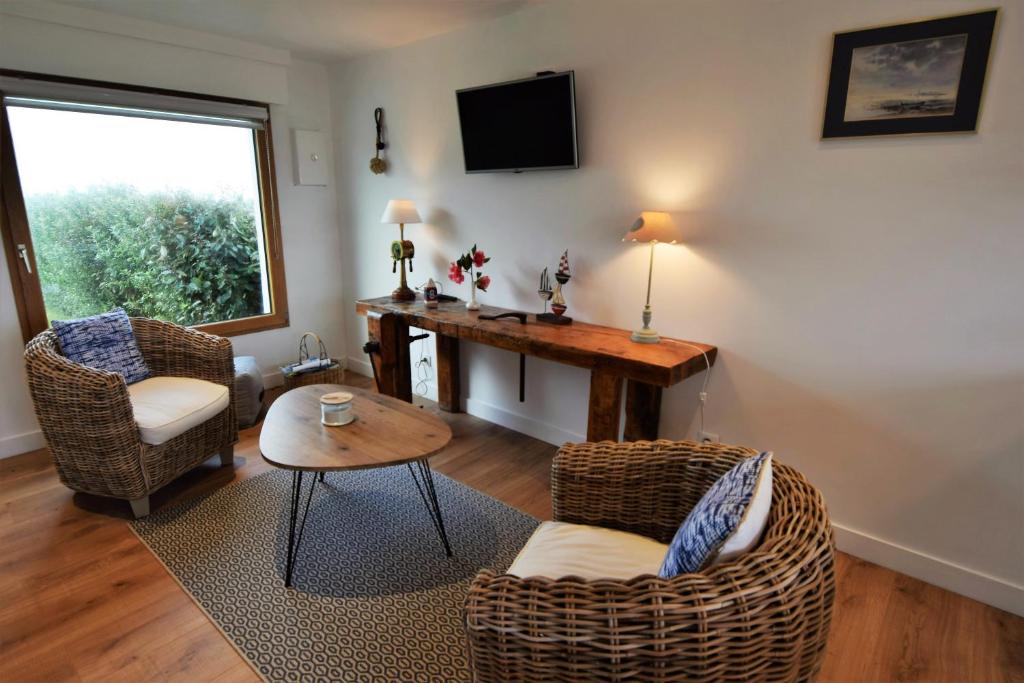 uma sala de estar com uma secretária, cadeiras e uma mesa em Duplex face à l'Océan-Penhors em Pouldreuzic