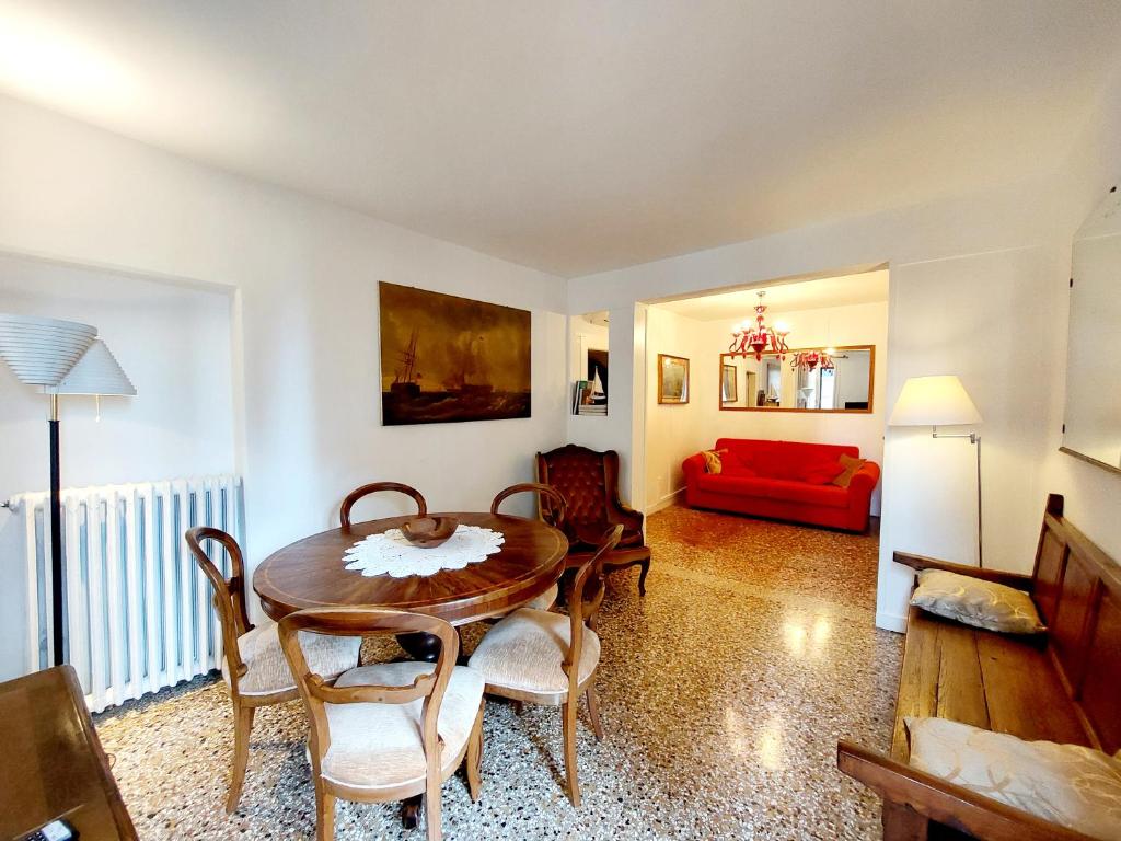 een woonkamer met een tafel en stoelen en een rode bank bij Cà Lina in Venetië