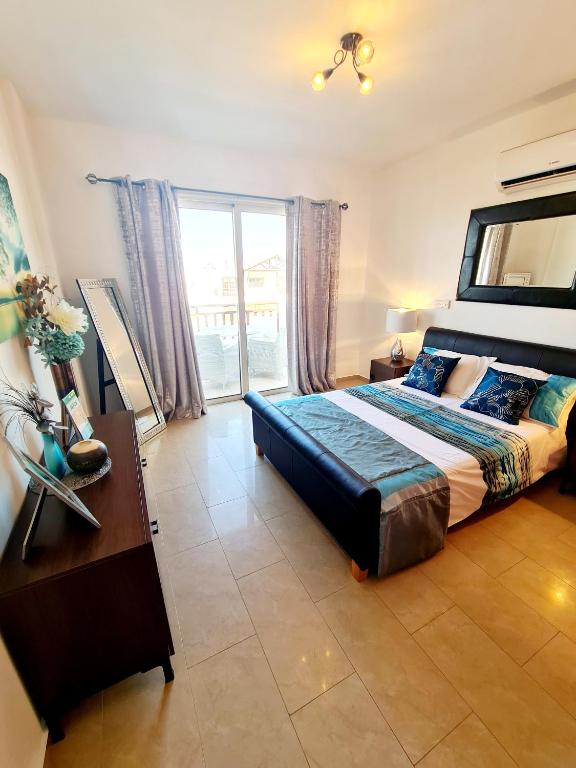 a bedroom with a bed and a table and a window at Stunning apartment C106 with balcony looking over pool in Peyia