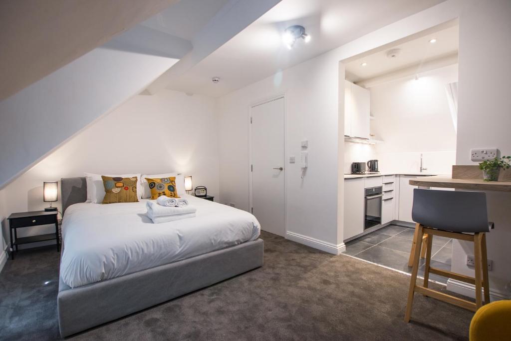a white bedroom with a bed and a kitchen at Bright & Beautiful Studio Flat in Bristol! in Bristol