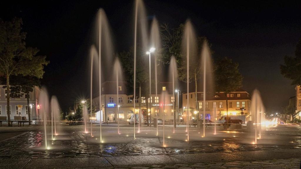 um grupo de fontes de água em uma cidade à noite em Pension Markt Neustrelitz em Neustrelitz